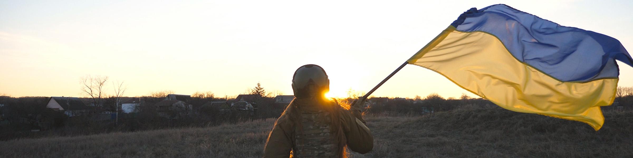 Female ukrainian army soldier runs and waves flag of Ukraine at sunset