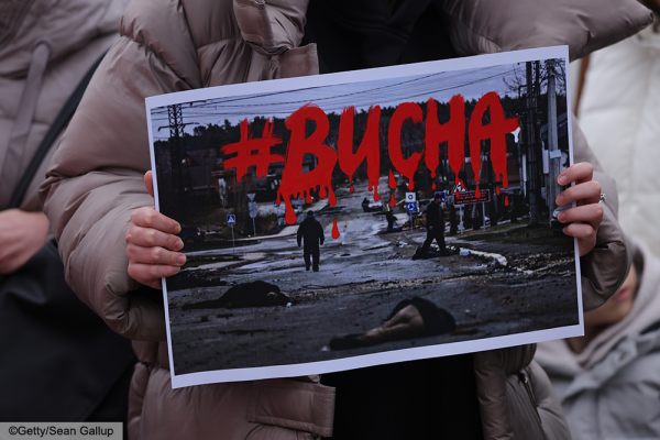 woman holding a poster that reads Bucha